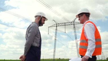 İletişim hatları yakınında çalışan iki mühendis. Elektrik direkleri