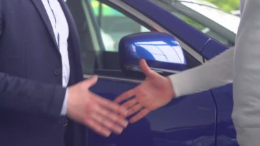 Otomobil satıcısı ve araba alan bir adam el sıkışıyor. Teknoloji ve insanlar kavramı