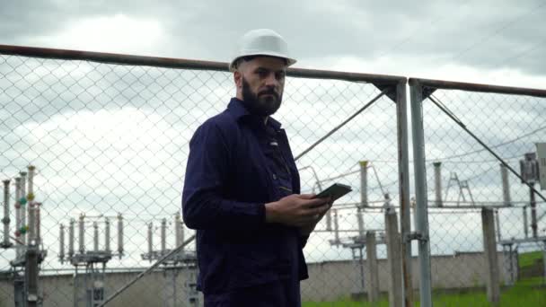 Ingeniero trabajando cerca de la central eléctrica. Rendimiento del sistema de monitoreo masculino y toma notas en el programa — Vídeos de Stock