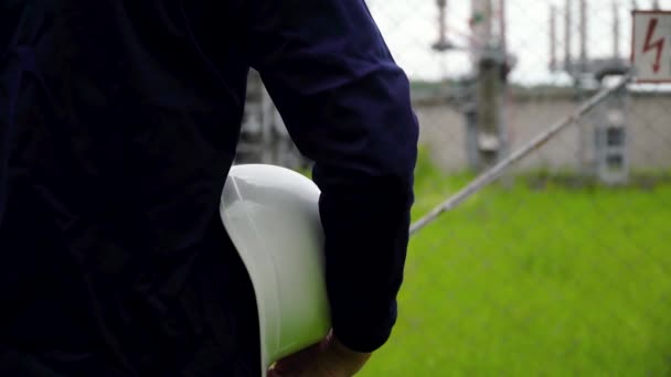 Arbeiter in Uniform und weißem Helm auf dem Hintergrund des Kraftwerks — Stockvideo