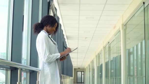 Medico o infermiere donna in ospedale prendere appunti. Primo piano del medico afro-americano in ospedale — Video Stock