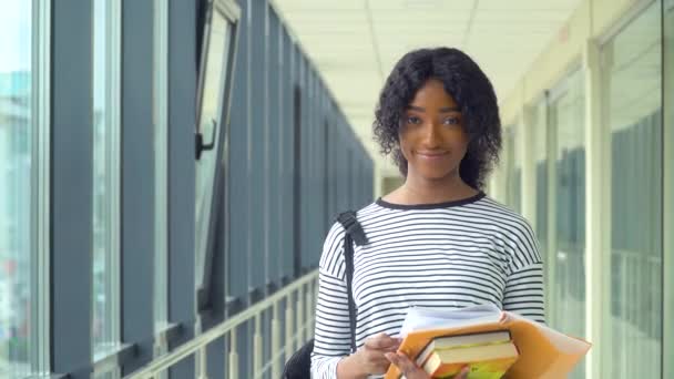 Afroamerikanische Studentin mit einem Buch an der Universität. Neue moderne, voll funktionsfähige Bildungseinrichtung. Konzept der Online-Bildung — Stockvideo