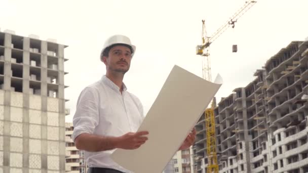 Arquiteto ou engenheiro trabalhando no projeto de construção de chapéus duros do canteiro de obras com plano de planta — Vídeo de Stock