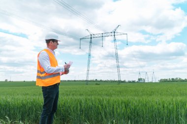 İletişim hatlarının yakınında çalışan bir mühendis. Elektrik mühendisi yüksek voltaj hatlarını kontrol ediyor. Aktarım kuleleri. Enerji verimliliği kavramı
