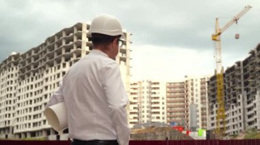 Erkek inşaatçı, inşaat alanının planlarını okuyan bir mimar. İnşaat konsepti