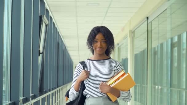 Estudiante afroamericana con un libro en la universidad. Nueva instalación educativa moderna totalmente funcional. Concepto de educación en línea — Vídeos de Stock