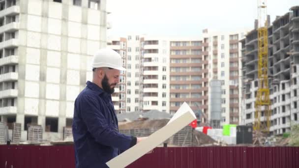 Architect of ingenieur werkzaam in harde hoed browsen bouwproject van de bouwplaats met blauwdruk plan — Stockvideo