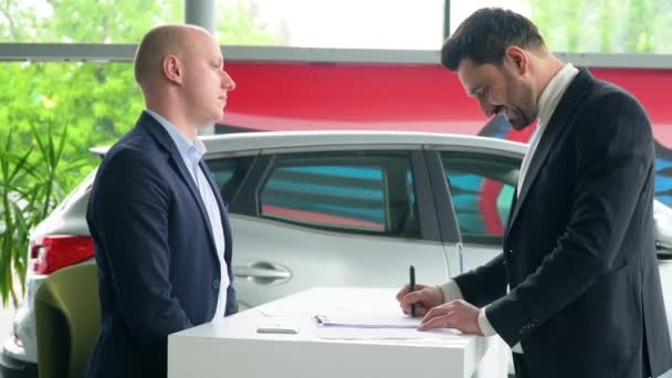 Venditore e acquirente firmano un contratto di acquisto di auto. Uomo d'affari che compra un'auto — Video Stock