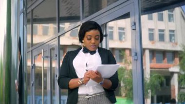 Modern ofis binasının yakınında belgeleri olan Afrikalı Amerikalı genç bir iş kadını. Karantinanın sonu