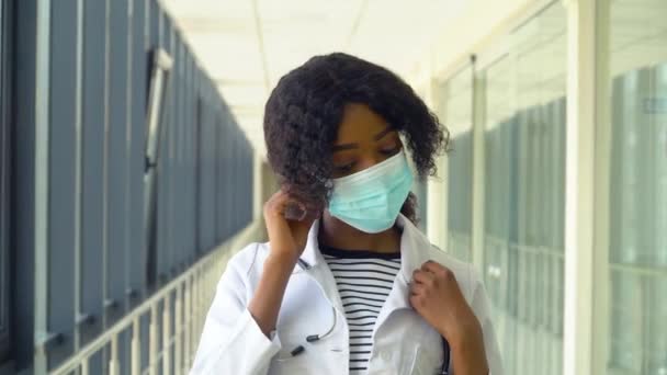 Afro-Amerikaanse vrouwelijke arts verwijdert een medisch masker in de moderne kliniek. Einde quarantaine. Stop het virus — Stockvideo