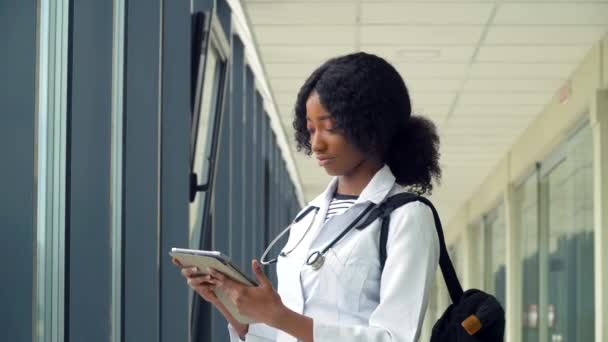 Afro-Amerikaanse studente met een tablet in het ziekenhuis. Nieuwe moderne volledig functionele medische faciliteit. Begrip geneeskunde, gezondheidszorg en mensen, online onderwijs — Stockvideo