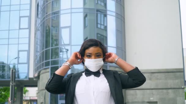 Afroamerikanische Geschäftsfrau setzt sich in der Nähe eines modernen Büros eine medizinische Maske auf. Virus stoppen — Stockvideo