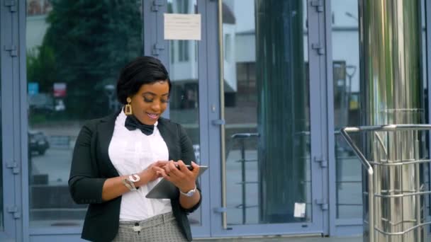 Afro-Amerikaanse jonge zakenvrouw met documenten in de buurt van modern kantoorgebouw. Einde van de quarantaine — Stockvideo