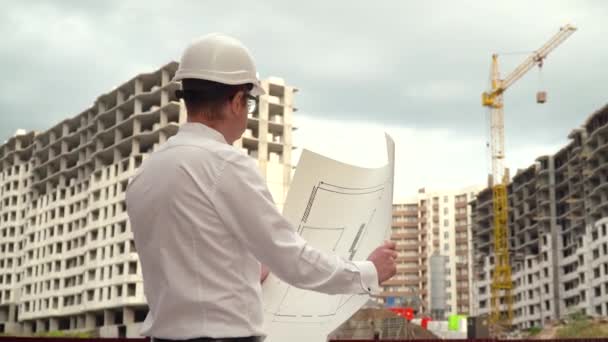 Architecte ingénieur constructeur masculin en casque dur lecture plan sur le chantier de construction — Video