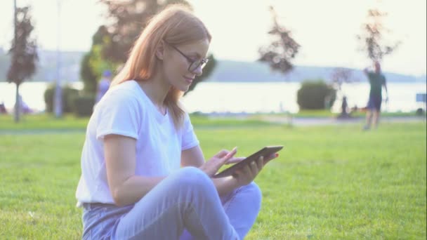 Jonge vrouw in freelance werk op tablet in een park. werk op afstand — Stockvideo