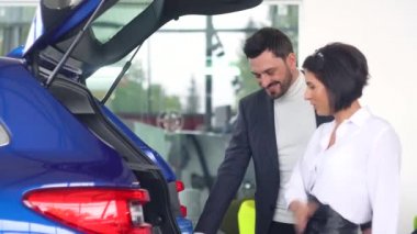 Profesyonel araba satıcısı, ilgili alıcıya, motor fuarında bagajı açık olan lüks bir arabadan bahsediyor.
