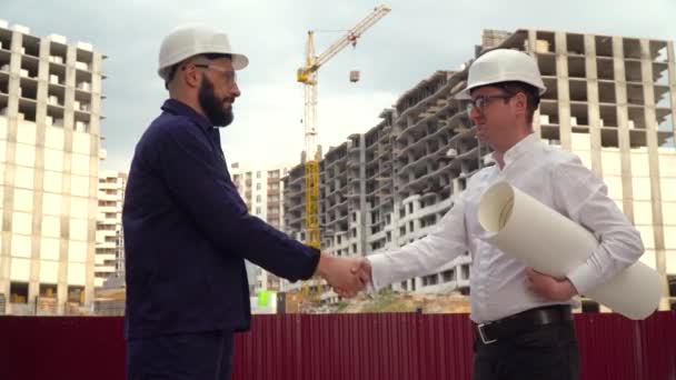 Architekt oder Ingenieur arbeitet, blättert Bauprojekt der Baustelle mit Bauplan. Bauarbeiter beim Händeschütteln — Stockvideo