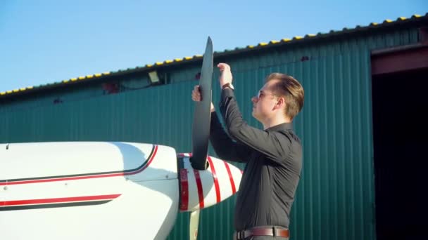 Vista lateral de un piloto macho gira una hélice de avión — Vídeos de Stock