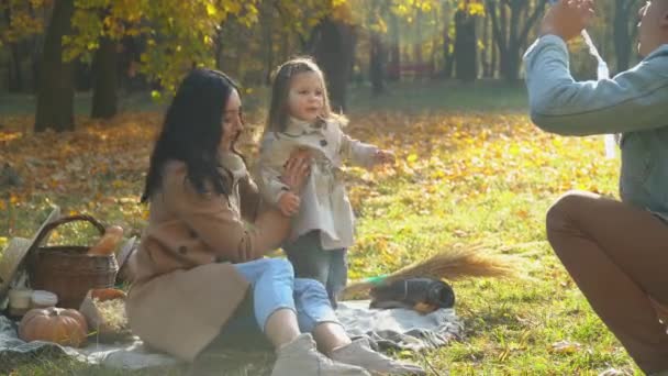 Familia soplando burbujas de aire. Madre y padre con hija divirtiéndose al aire libre. Picnic en el parque de otoño — Vídeo de stock