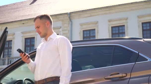 Empresario hablando por teléfono al aire libre cerca del coche. Concepto de tecnología y personas — Vídeo de stock