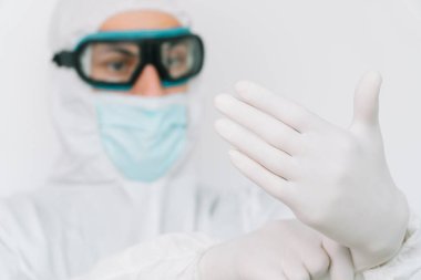Virolog, virüs salgını sırasında koruyucu giysiler giyip portre çiziyor. Klinikte ya da hastanede beyaz arkaplanda takım elbise, maske, eldiven ve gözlük