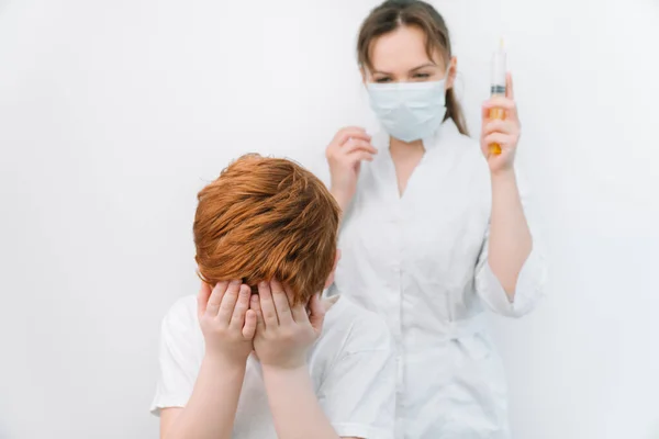 El niño tiene miedo del médico con una jeringa. Bebé llora miedo inyección —  Fotos de Stock