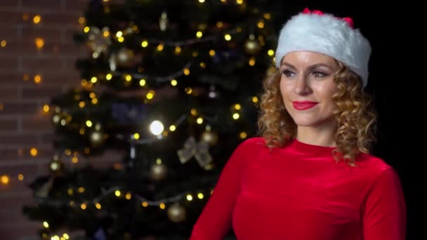 Portret van jonge mooie dame in kerstman kerstkostuum in de buurt van kerstboom — Stockvideo