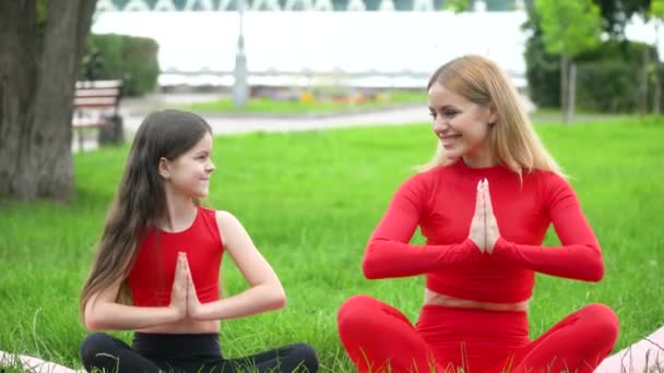 Frau mit Tochter beim Yoga im Park. Gesunder Lebensstil — Stockvideo