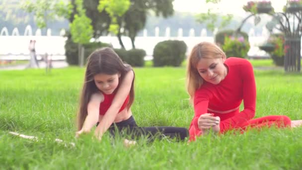 Mujer joven con hija entrena en el parque. concepto de estilo de vida saludable — Vídeos de Stock