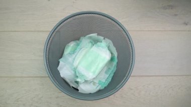 Kadın kirli bezleri çöpe atıyor. Kullanılmış bebek bezlerinden kurtulmak. Çevre kirliliği