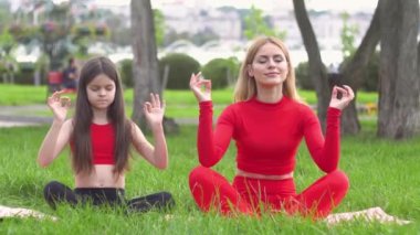 Kızı olan bir kadın parkta yoga yapıyor. Sağlıklı yaşam tarzı kavramı