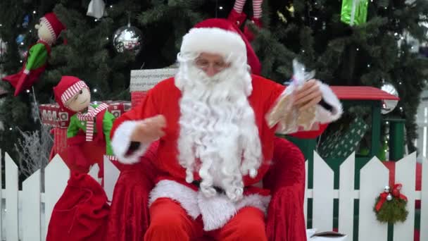Санта Клаус кладет подарок в мешок в торговом центре — стоковое видео