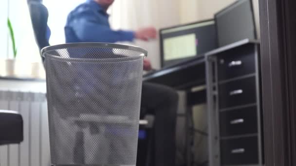 사무직 근로자가 으스러진 종이를 쓰레기통에 버렸다. 사무실을 배회하는 사업가는 종이를 쓰레기통에 던진다 — 비디오