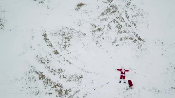 De kerstman ligt op het besneeuwde strand. Bovenaanzicht. Camera naar beneden. Kerstman in het noorden — Stockvideo