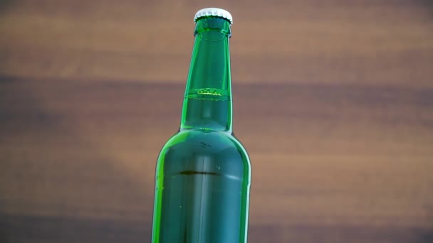 Una botella de cerveza fría sobre un fondo marrón. Rotación 360 grados — Vídeos de Stock