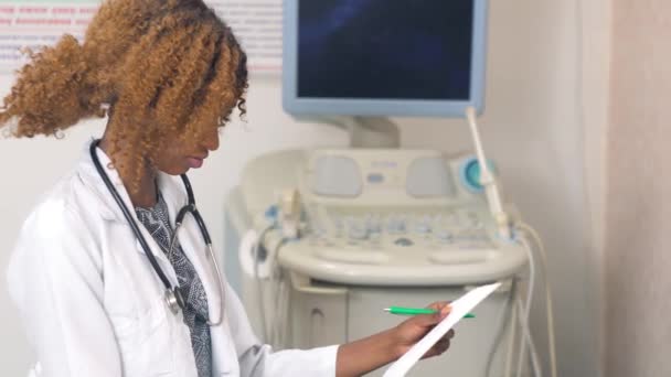 Enfermera afroamericana con un cuaderno en el hospital moderno. Concepto de medicina, salud y personas — Vídeo de stock