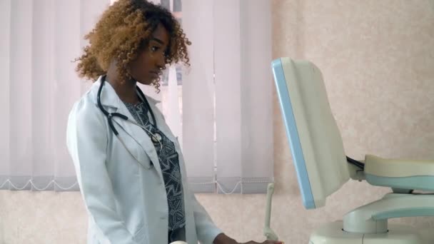 アフリカ系アメリカ人女性医師が患者を診察する。超音波デバイスはクローズアップを監視します。医療機器の所持 — ストック動画