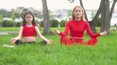 Güzel ve sağlıklı kadın ve küçük kız nilüfer çiçeği ya da sukhasna pozunda oturur, meditasyon yapar ya da yoga ve pranayama yapar. Doğada beden ve zihin gevşesin.