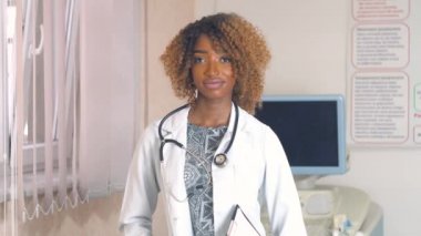 Arka planda ultrason cihazlarıyla hastanede steteskoplu profesyonel Afro-Amerikan kadın doktor portresi. Virüsü durdur