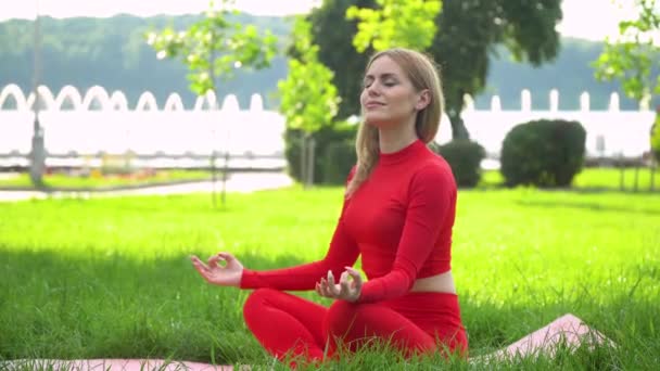 Woman in red practices yoga at park. Healthy lifestyle concept — Stock Video