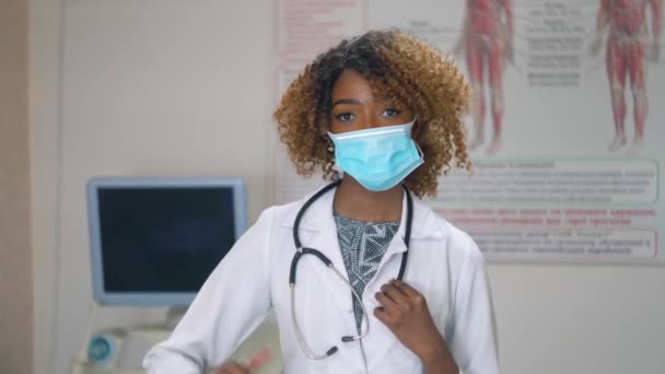 Porträtt av professionell afrikansk amerikansk kvinnlig läkare i medicinsk mask. Sjukhus med ultraljudsanordningar på bakgrunden. Stoppa viruset — Stockvideo