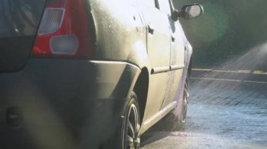 Araba yıkama servisi. Bir adam makineyi yüksek basınçlı ekipmanla yıkıyor.