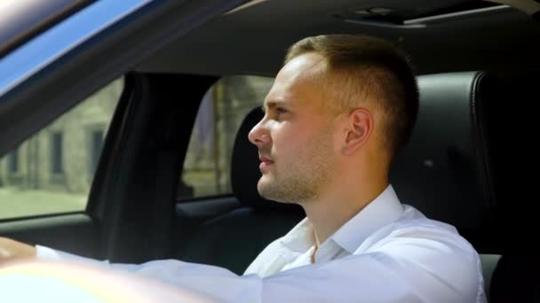 Hombre con estilo en una camisa blanca sentado en el salón de coches — Vídeo de stock