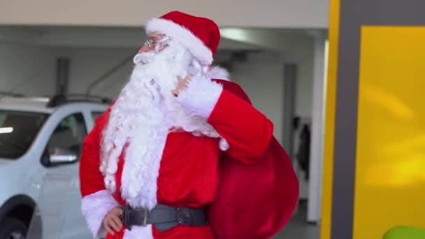 Santa Claus w salonie samochodowym wybiera samochód prezent — Wideo stockowe