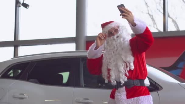 Papai Noel tirando uma selfie em um concessionário de carros — Vídeo de Stock