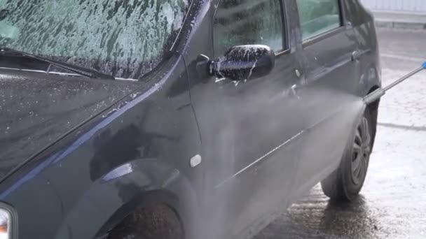 Um homem a lavar carros na auto-lavagem. Lavagem de carro self-service — Vídeo de Stock