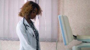 Profesyonel Afro-Amerikan Kadın Doğum Uzmanı jinekoloğun yüzü hamile bir kadının ultrasonunu çekiyor.