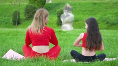 Güzel ve sağlıklı kadın ve küçük kız nilüfer çiçeği ya da sukhasna pozunda oturur, meditasyon yapar ya da yoga ve pranayama yapar. Doğada beden ve zihin gevşesin.