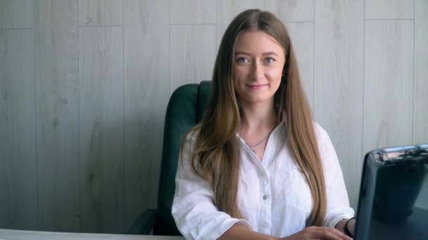 Mulher caucasiana feliz trabalhando no computador portátil olhando para a câmera e smilling. Bom dia de trabalho — Vídeo de Stock