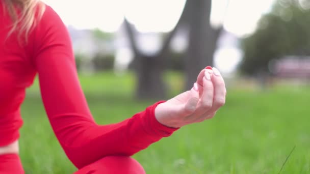Mujer caucásica joven disfrutar del yoga en el parque. Primer plano de las manos. Posición de loto. concepto de estilo de vida saludable — Vídeo de stock